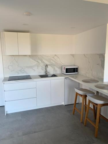 a kitchen with white cabinets and a sink and stools at Guest house - Ocean views in Rye