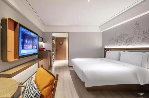 a bedroom with a large white bed and a flat screen tv at Shantou New Town Huanghe Road Yifei Hotel in Xialian