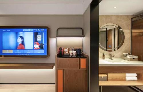 a bathroom with a tv and a bathroom with a sink at Shantou New Town Huanghe Road Yifei Hotel in Xialian