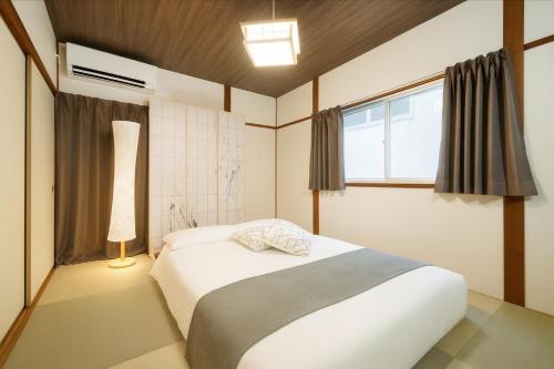 a bedroom with a large white bed with a window at 憩いの家 昭代 in Fukuoka