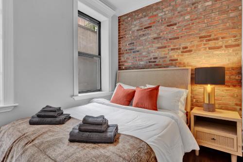 a bedroom with a bed with a brick wall at Elegant 3BR-2BA in Gramercy -Modern & Central in New York