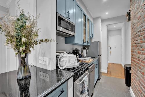 a kitchen with blue cabinets and a vase of flowers at Elegant 3BR-2BA in Gramercy -Modern & Central in New York