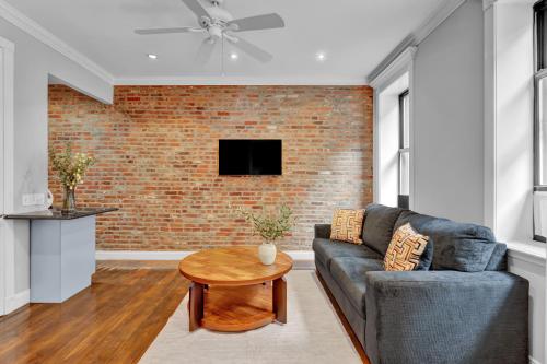 a living room with a couch and a brick wall at Elegant 3BR-2BA in Gramercy -Modern & Central in New York