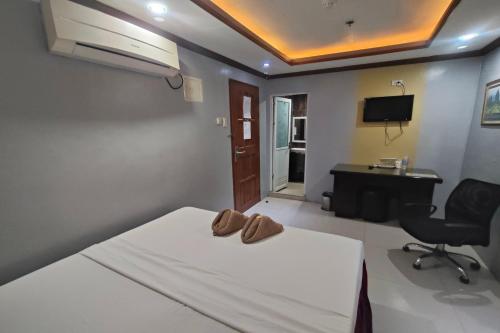 a bedroom with a bed with a desk and a chair at Taj Hotel Tuguegarao in Tuguegarao City