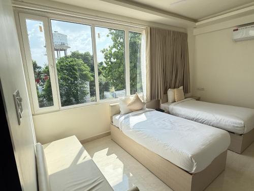 een hotelkamer met twee bedden en een raam bij Hotel Crown Plaza in Prayagraj