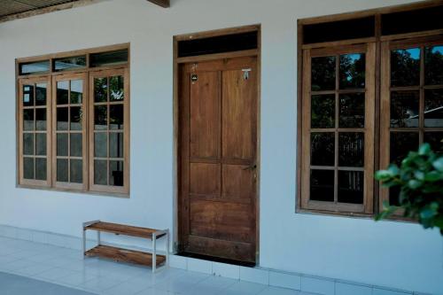 a pair of doors and a bench on a white wall at Desa Huis Yogyakarta in Gandok