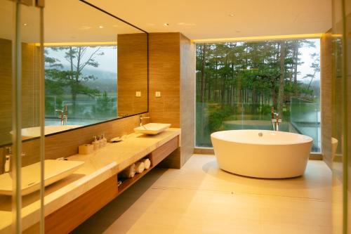 a bathroom with two sinks and a tub and a large window at Haven in the Pines in Ðinh An (2)