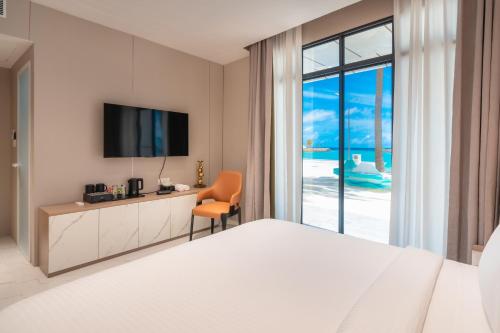 a hotel room with a bed and a desk and a television at Wings by Hawks Hotels Kamadhoo Baa Atoll in Kamadhoo