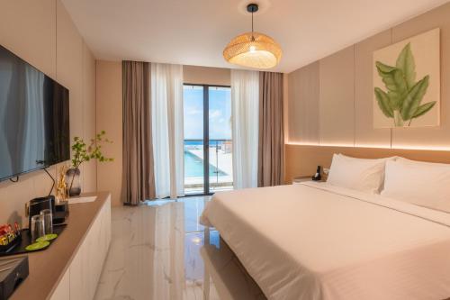 a hotel room with a bed and a large window at Wings by Hawks Hotels Kamadhoo Baa Atoll in Kamadhoo