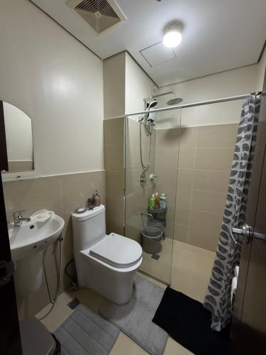 a bathroom with a toilet and a shower and a sink at Paseo Verde at Real in Manila