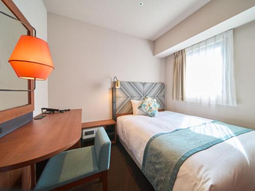 a hotel room with a bed and a desk and a window at Meitetsu Inn Nagoya Kanayama Annex in Nagoya