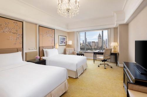 a hotel room with two beds and a desk and a television at Pudong Shangri-La Shanghai - With a sweeping view of the Pearl Tower and the historic Bund skyline in Shanghai
