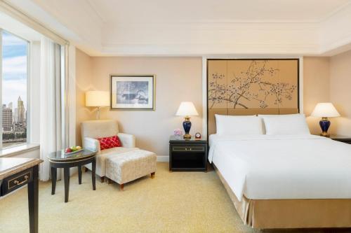 a hotel room with a bed and a chair at Pudong Shangri-La Shanghai - With a sweeping view of the Pearl Tower and the historic Bund skyline in Shanghai