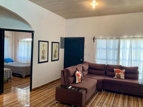 a living room with a brown couch and a bedroom at Joy & peace house in Tela