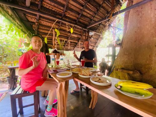 a man and a woman sitting at a table with food at Chika's Place River View Udawalawa in Udawalawe