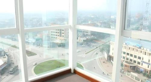 three windows in a building with a view of a city at BMC Ha Tinh hotel in Ha Tinh