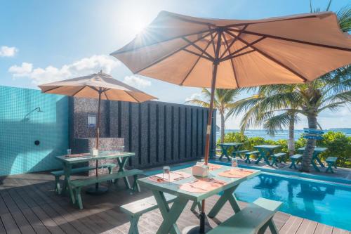 a patio with tables and umbrellas next to a pool at Wings by Hawks Hotels Kamadhoo Baa Atoll in Kamadhoo