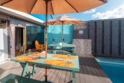 a table with an umbrella next to a pool at Wings by Hawks Hotels Kamadhoo Baa Atoll in Kamadhoo