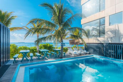 a swimming pool with tables and chairs next to a building at Wings by Hawks Hotels Kamadhoo Baa Atoll in Kamadhoo