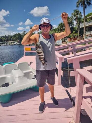 a man holding a fish while standing on a boat at The Mermaid on the Cotee River in Port Richey
