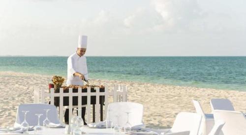 a chef standing on the beach with a table on the beach at Excellence Playa Mujeres- All Inclusive- Adults Only in Cancún