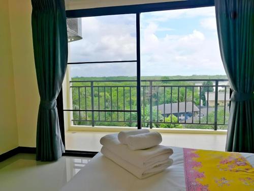 a room with a large window with towels on a bed at The Nest Krabi Hotel in Ao Nang Beach