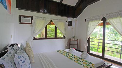 een slaapkamer met een bed en twee ramen bij Ocean 101 Beach Resort in General Luna