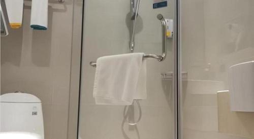 a shower with a glass door and a towel at City Comfort Inn Shenzhen Shiyan Science and Technology Park in Shenzhen