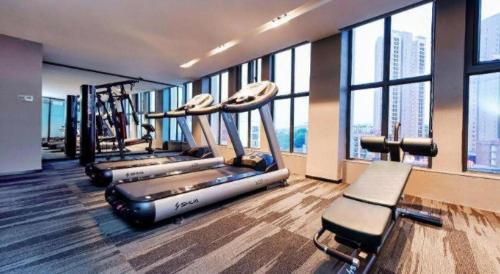 a gym with a row of treadmills and windows at Echarm Hotel Anshun High-speed Railway Station Jichang Road in Anshun