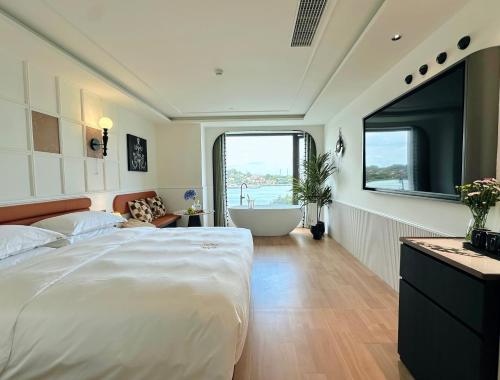 a bedroom with a large bed and a bath tub at 茑岛海景潮宿NiaoDao Seaview Hotel in Xiamen