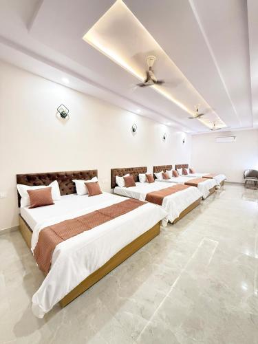 a row of four beds in a white room at Hotel Sai Inn in Amritsar