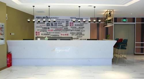 a white counter in a room with words on a wall at Magnotel Wulanhaote Hanshan Dong Street in Ulan Hot