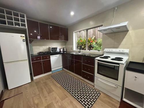 a kitchen with brown cabinets and white appliances at Cozy Corner in Auckland