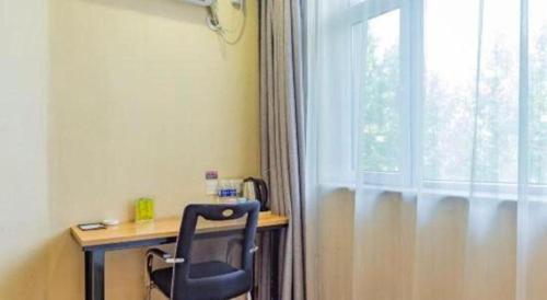a desk with a chair in a room with a window at PAI Hotels Shijiazhuang Railway Station West Square in Shijiazhuang