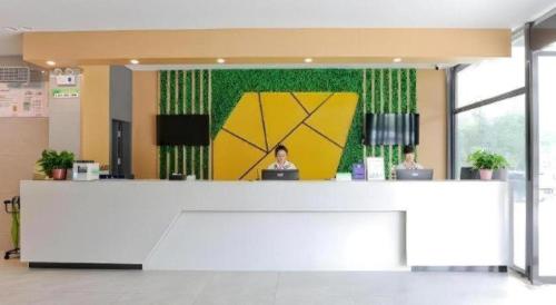 a woman sitting at a counter in an office at Vatica Hotel Hefei Yaohai Longgang Subway Station in Hefei