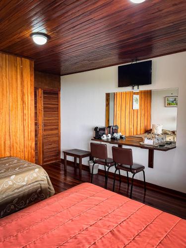 a bedroom with a bed and a desk with chairs at Hotel Montaña Monteverde in Monteverde Costa Rica