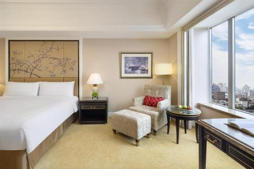 a bedroom with a bed and a chair and a desk at Pudong Shangri-La Shanghai - With a sweeping view of the Pearl Tower and the historic Bund skyline in Shanghai