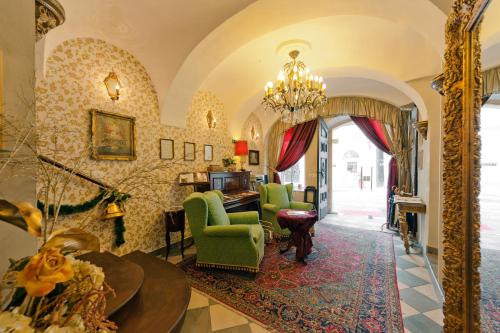 d'un salon avec un lustre et des chaises vertes. dans l'établissement Allegro Hotel, à Ljubljana