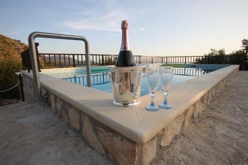 a bottle of wine and two wine glasses on a wall by a pool at Tenuta Palma in Sonnino