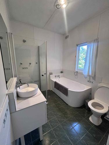 a bathroom with a tub and a sink and a toilet at Akarana Cottage in Leura