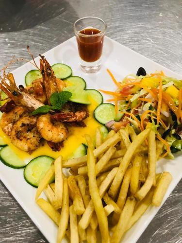 a plate of food with shrimp and french fries at Guru Beach Resort in Tangalle