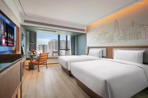 a hotel room with two beds and a flat screen tv at Shantou New Town Huanghe Road Yifei Hotel in Xialian