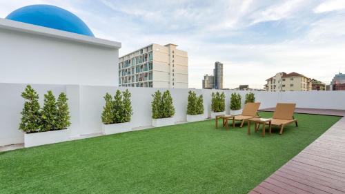 a rooftop garden with grass and chairs on a building at Downtown Oasis 芭提雅市中心独栋泳池别墅 A 5卧6卫 KTV BBQ 芭提雅海滩步行街500m in Pattaya South