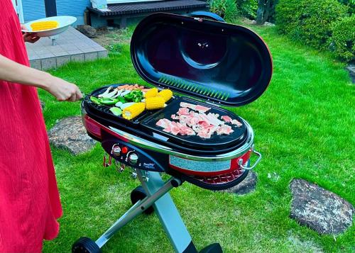a woman is cooking food on a grill at Sealine Retreat Atami Onsen BBQ & hot spring & movies in a villa overlooking the sea! Private and relaxing in Atami