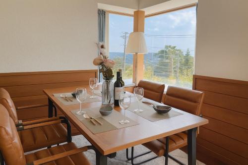 a table with wine glasses and a vase with flowers on it at Sealine Retreat Atami Onsen BBQ & hot spring & movies in a villa overlooking the sea! Private and relaxing in Atami