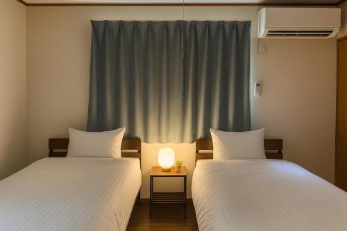 two beds sitting next to each other in a room at Sealine Retreat Atami Onsen BBQ & hot spring & movies in a villa overlooking the sea! Private and relaxing in Atami
