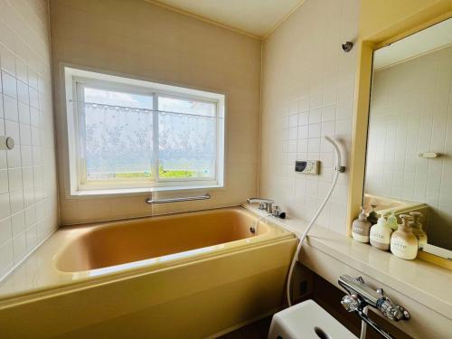 a bathroom with a large tub and a window at Sealine Retreat Atami Onsen BBQ & hot spring & movies in a villa overlooking the sea! Private and relaxing in Atami