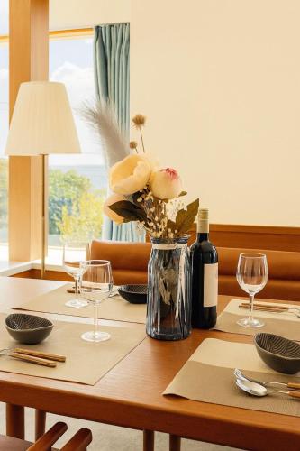 a vase of flowers on a table with wine glasses at Sealine Retreat Atami Onsen BBQ & hot spring & movies in a villa overlooking the sea! Private and relaxing in Atami