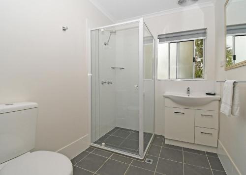 un bagno bianco con doccia e lavandino di Coast Apartments 2 bedroom Hideaway a Torquay