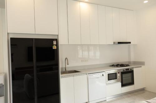 a kitchen with white cabinets and a stove top oven at Aviv Villa Samui in Amphoe Koh Samui